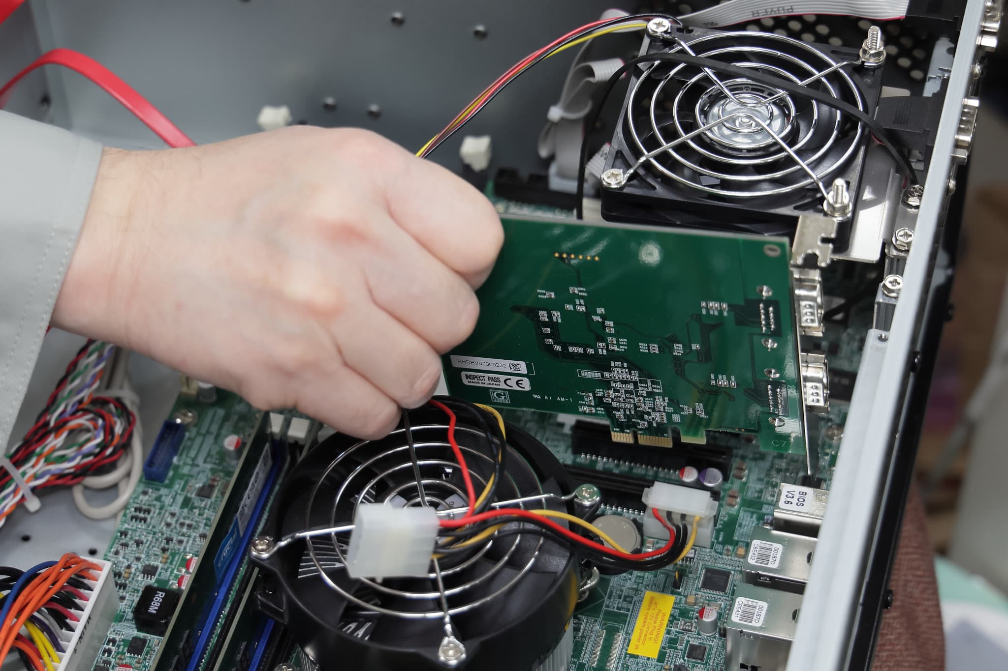 基盤にパーツを取り付ける男性