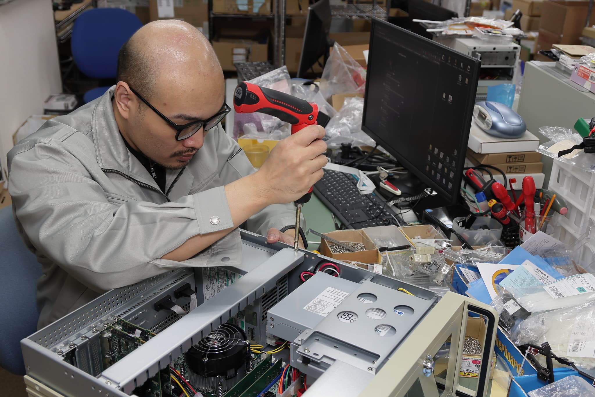 パソコンの基盤にパーツをはめる作業員